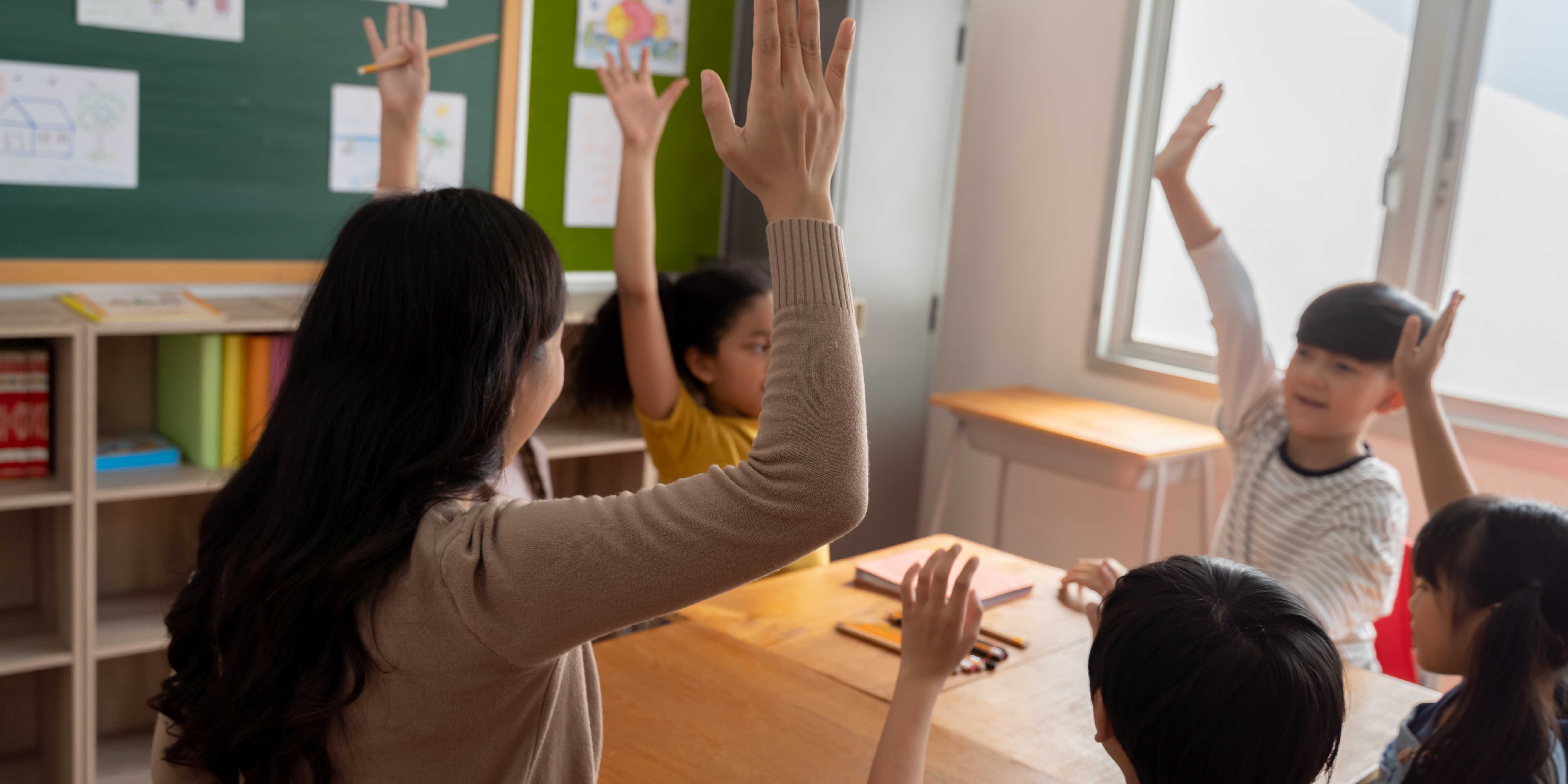 Kids raising their hands in classroom - co-creating norms